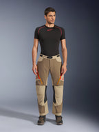 Alpinestars Maxdura Dual bukser, adventure- og dual-sport kørebukser, Walnut Aluminum, her vist med sort kortærmet kompressionsshirt og adventure-støvler, orange lynlåsventiler og røde logoer på lårene, sort taljebælte med spænde, over-støvle-design til motorcykelkørsel.