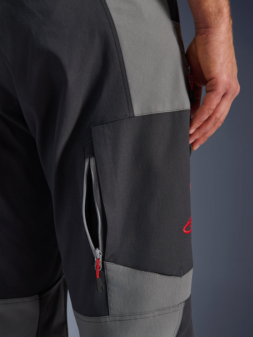 Alpinestars Maxdura Dual bukser, adventure motorcykelbukser i Dark Gray og Deep Gray, nærbillede af låret med en ventilationsåbning med lynlås og rødt broderet logo, slidstærk stretch polyamid-konstruktion.