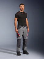 Alpinestars Maxdura Dual Pants, adventure motorcykelbukser, mørkegrå og dybgrå, bæres med et sort basislag og støvler, med røde ventilationsåbninger med lynlås, forstærkede paneler på knæ og sæde og en talje med bælte, atletisk pasform til dual-sport-kørsel