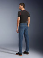Alpinestars Flex-AST 5 Denim bukser, Indigo Washed, model set bagfra iført bukserne, urbane motorcykeljeans, afsmalnende pasform med monolags stretch denim, kombineret med en sort t-shirt og sorte sneakers