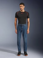 Alpinestars Flex-AST 5 Denim bukser, Indigo Washed blå denim motorcykelbukser, regular tapered pasform, båret af en model med et sort Alpinestars baselayer og sorte casual sko, urbant livsstilstøj til motorcykelkørsel.