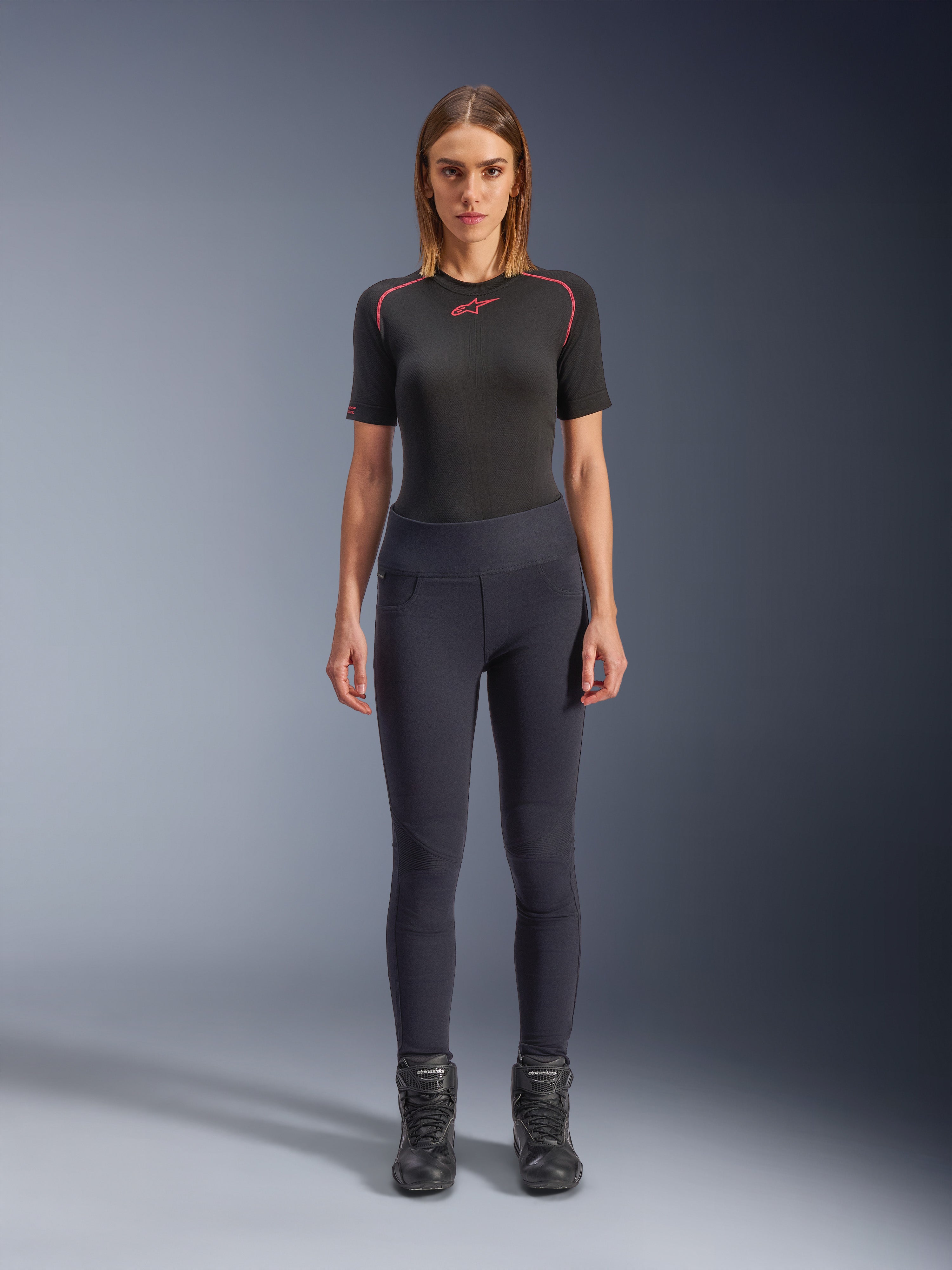 Alpinestars Stella Flex-Ast leggings, motorcykel-leggings til kvinder, sorte, båret med en sort kortærmet top med røde detaljer og sorte kørestøvler, moderne urban køreudstyr i slim-fit, set forfra