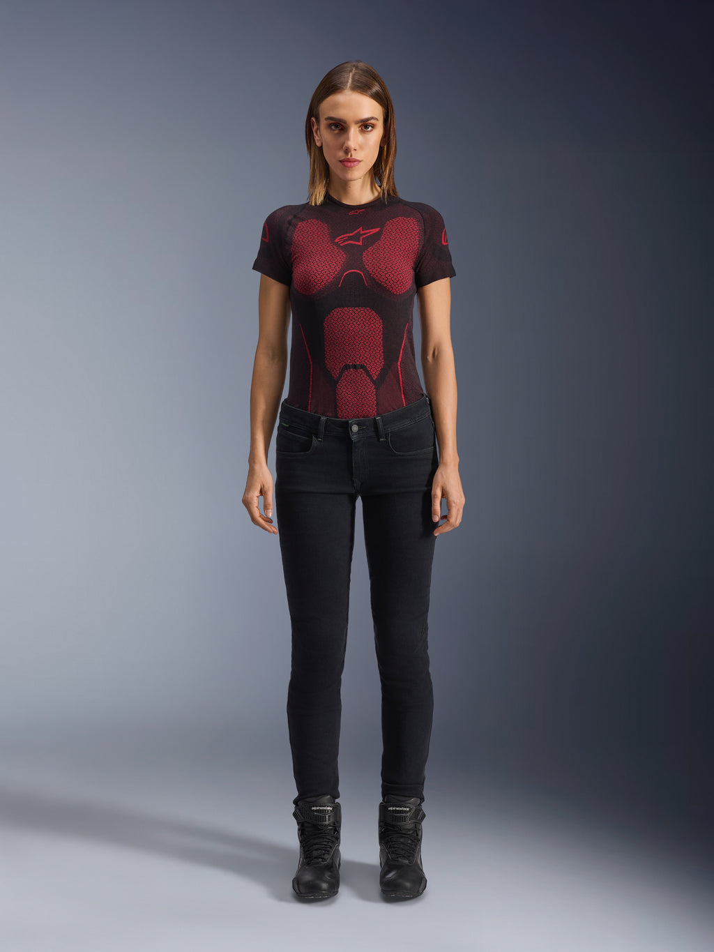 Alpinestars Daisy V3 kører-jeans til damer, Rinse Black, slim-fit motorcykelbukser, vist på en model med en rød og sort mønstret teknisk t-shirt og sorte motorcykelstøvler, casual urbant køreudstyr med en feminin silhuet og design med høj talje.