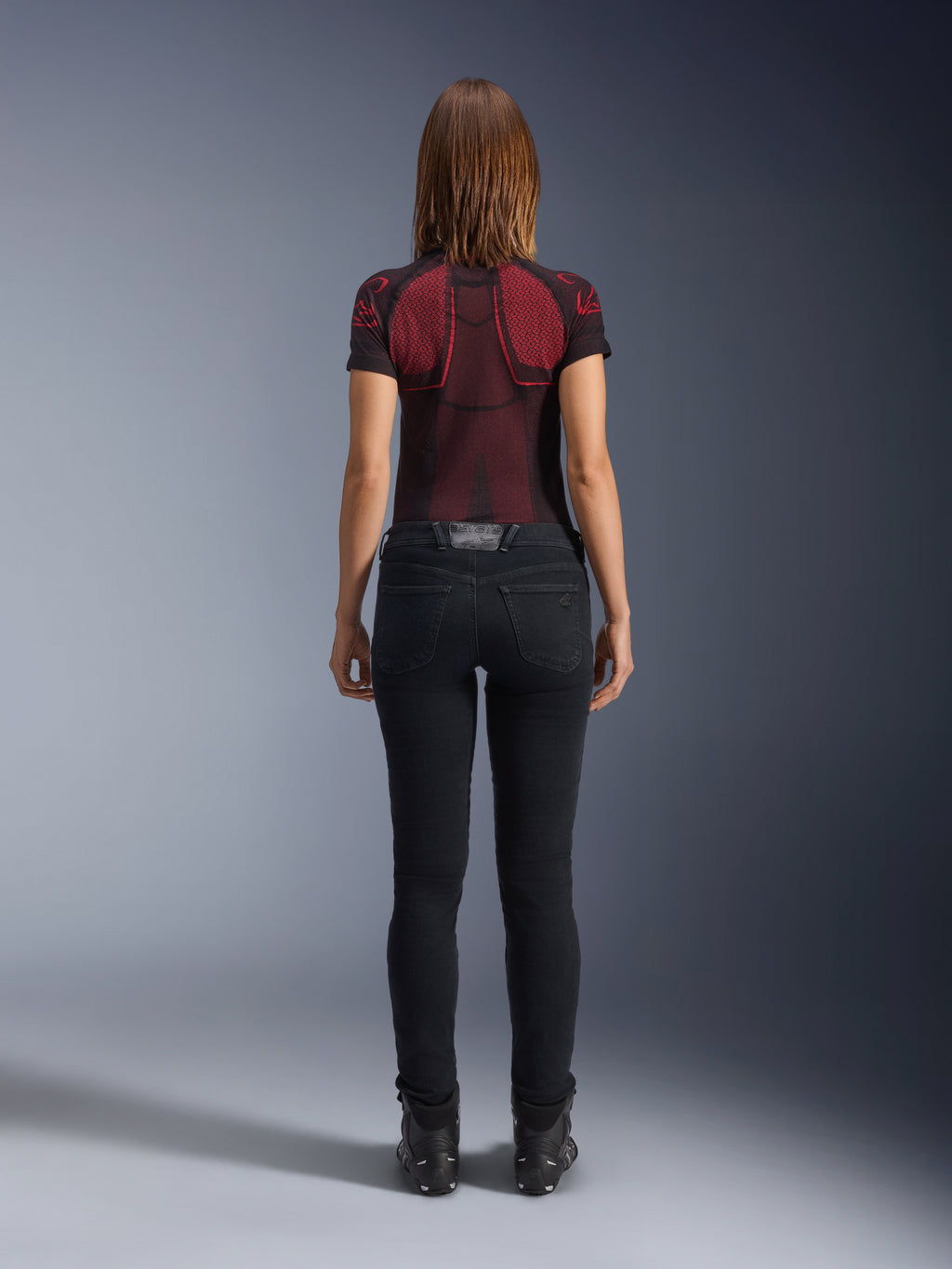 Alpinestars Daisy V3 motorcykeljeans til damer, Rinse Black, slim fit bukser set bagfra, design med høj talje og baglommer, stylet med rød og sort mønstret teknisk trøje og sorte støvler, urbant mc-udstyr til kvinder