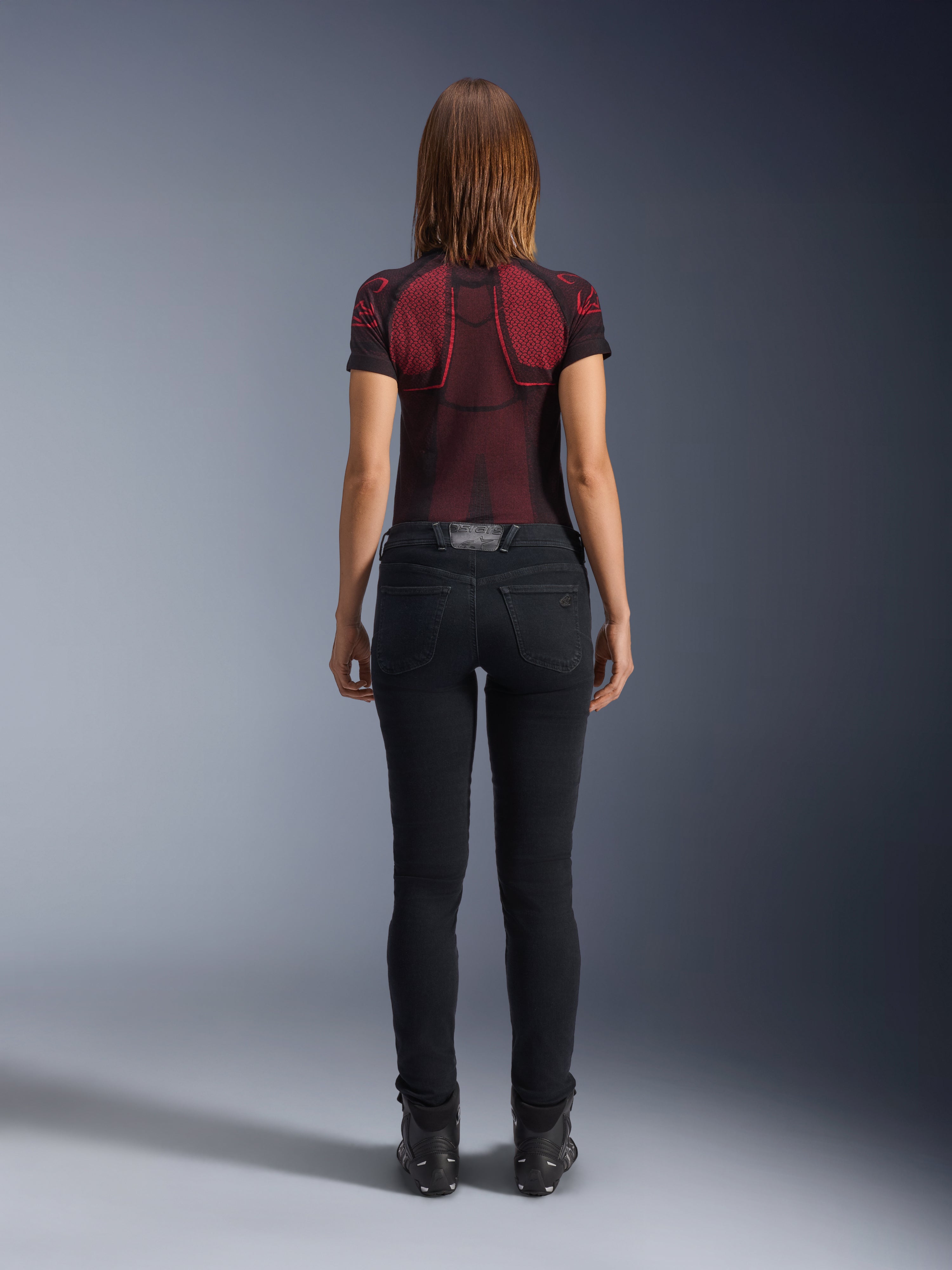 Alpinestars Daisy V3 motorcykeljeans til damer, Rinse Black, slim fit bukser set bagfra, design med høj talje og baglommer, stylet med rød og sort mønstret teknisk trøje og sorte støvler, urbant mc-udstyr til kvinder