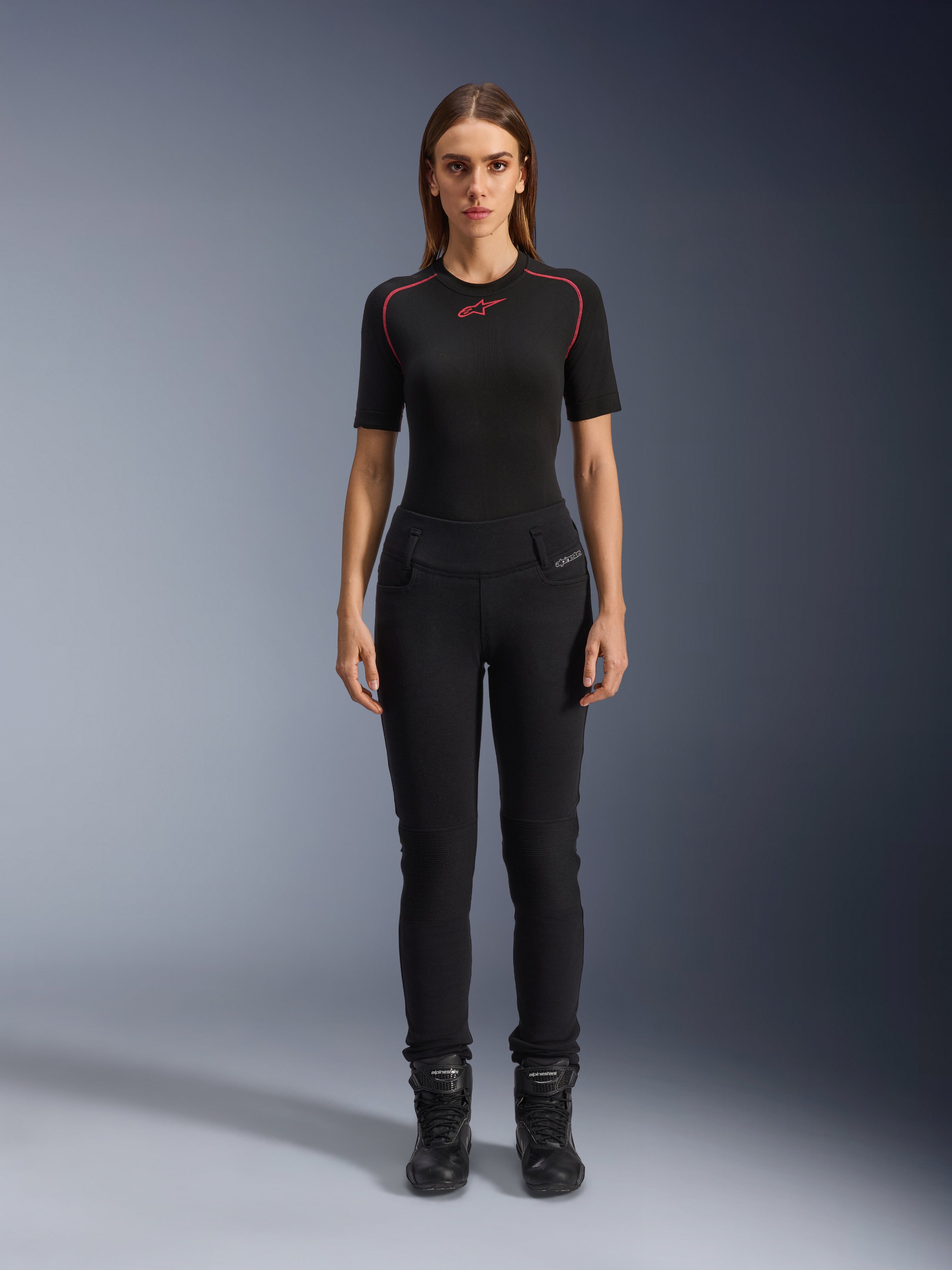 Alpinestars Womens Banshee Leggings, sorte motorcykel-leggings, kropsnær anatomisk pasform, båret af en kvindelig model med et sort basislag og motorcykelstøvler, med ribbede knæpaneler og højtaljet konstruktion til urban kørsel.