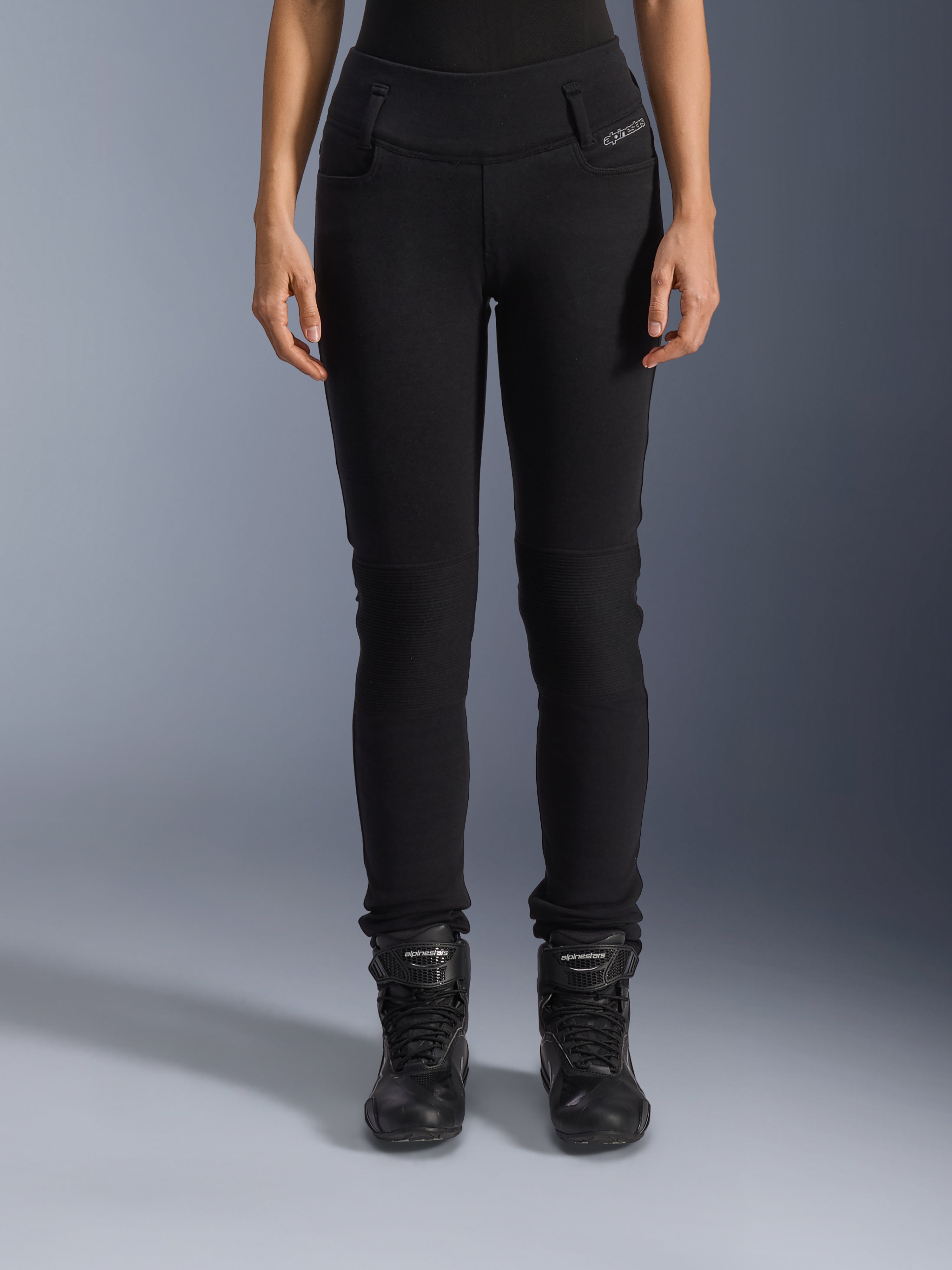 Alpinestars Banshee dame-leggings, sorte motorcykelbukser, slim-fit design med harmonika-knæpaneler, vist med sorte high-top kørestøvler, urbant køreudstyr i en afslappet stil