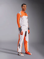 Alpinestars KMX-9 V3 Graphic 6 gokartdragt, hvid, orange og sort, med et plettet mønster og markante orange ærmer, båret af en model med matchende racerhandsker og sko, professionelt dobbeltlags motorsportudstyr.