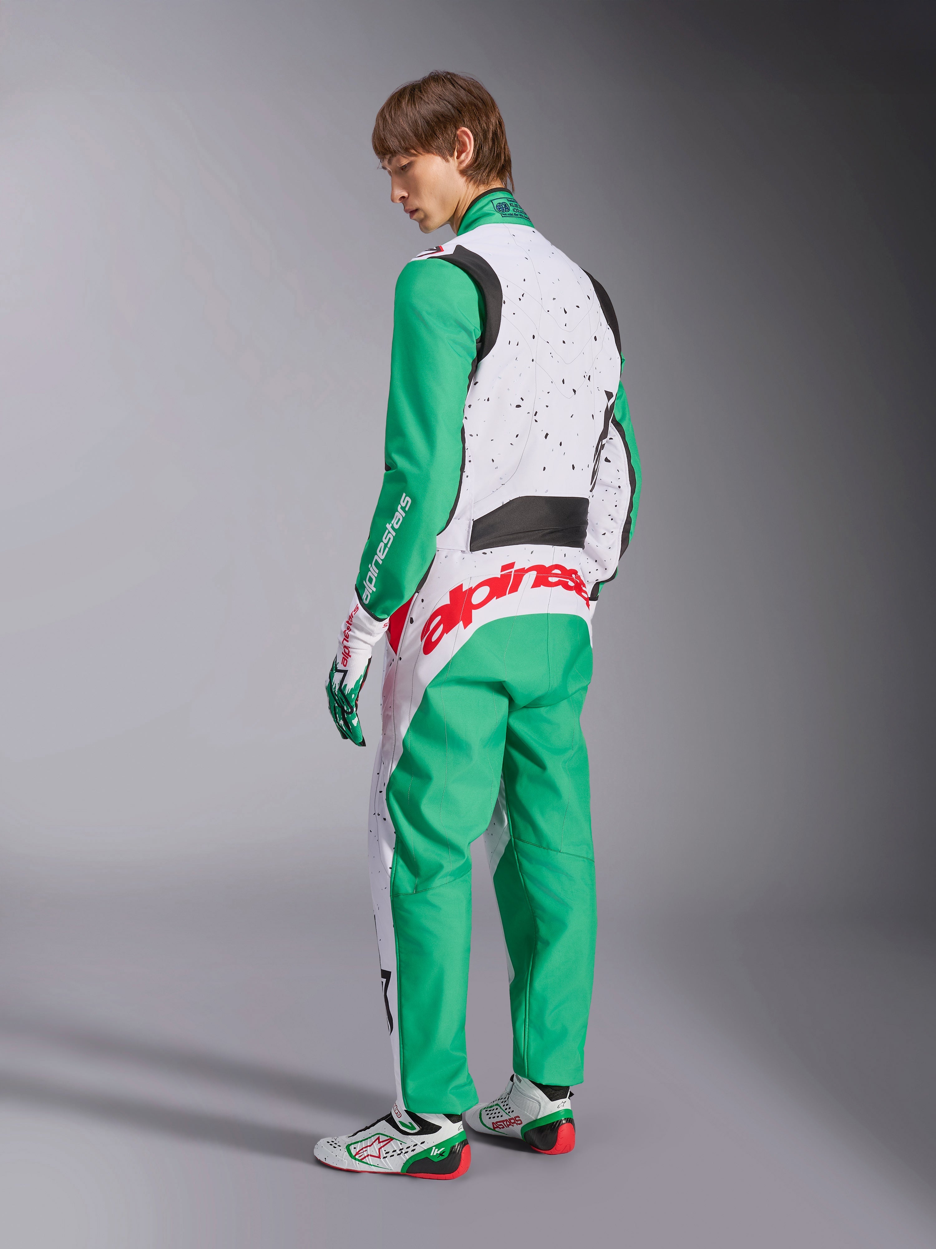 Alpinestars KMX-9 V3 Graphic 6 dragt, kartingdragt, hvid, grøn og rød, model set bagfra, med grønne ærmer og paneler forneden, hvid øvre overkrop med sorte nistrede detaljer, markant rød Alpinestars-branding på lænden, kombineret med matchende hvide og grønne kartingsko.