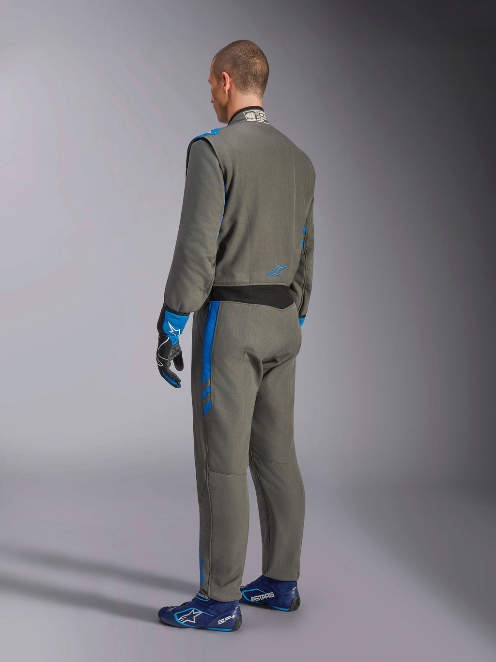 Alpinestars GP Race V3 Suit FIA, køredragt til biler, Antracitblå, set bagfra af model iført den grå heldragt med blå detaljer, matchende blå handsker og køresko, professionelt motorsportsudstyr