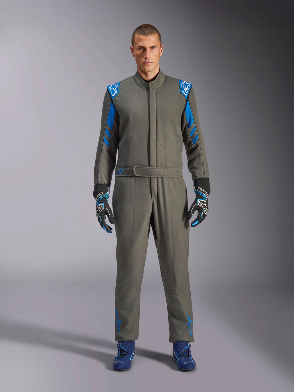 Alpinestars GP Race V3 Køredragt FIA, antracitblå motorsportdragt, båret med matchende handsker og køresko, med klare blå skulderepauletter og striber på ærmerne, Alpinestars-logodetaljer, professionel motorsportbeskyttelse til baneløb