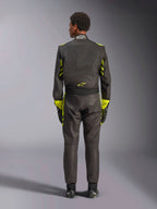 Alpinestars GP Race V3 Køredragt FIA, set bagfra, sort med neon-gule detaljer, med gule paneler på arme og overkrop, gult logo på lænden, båret med matchende racerhandsker og støvler, professionel racerdragt til bilsport.