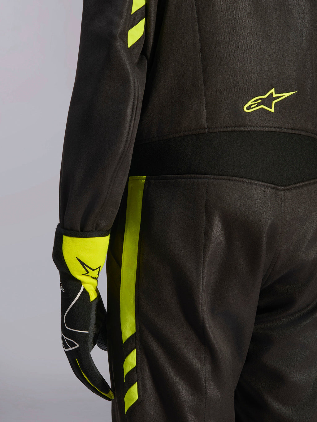 Alpinestars GP Race V3 Suit FIA, sort og gul fluo, nærbillede af detaljer på taljen og siden af benet, med aramid-strækpaneler og matchende racerhandske, professionelt bilsportsudstyr