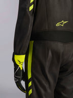 Alpinestars GP Race V3 Suit FIA, sort og gul fluo, nærbillede af detaljer på taljen og siden af benet, med aramid-strækpaneler og matchende racerhandske, professionelt bilsportsudstyr
