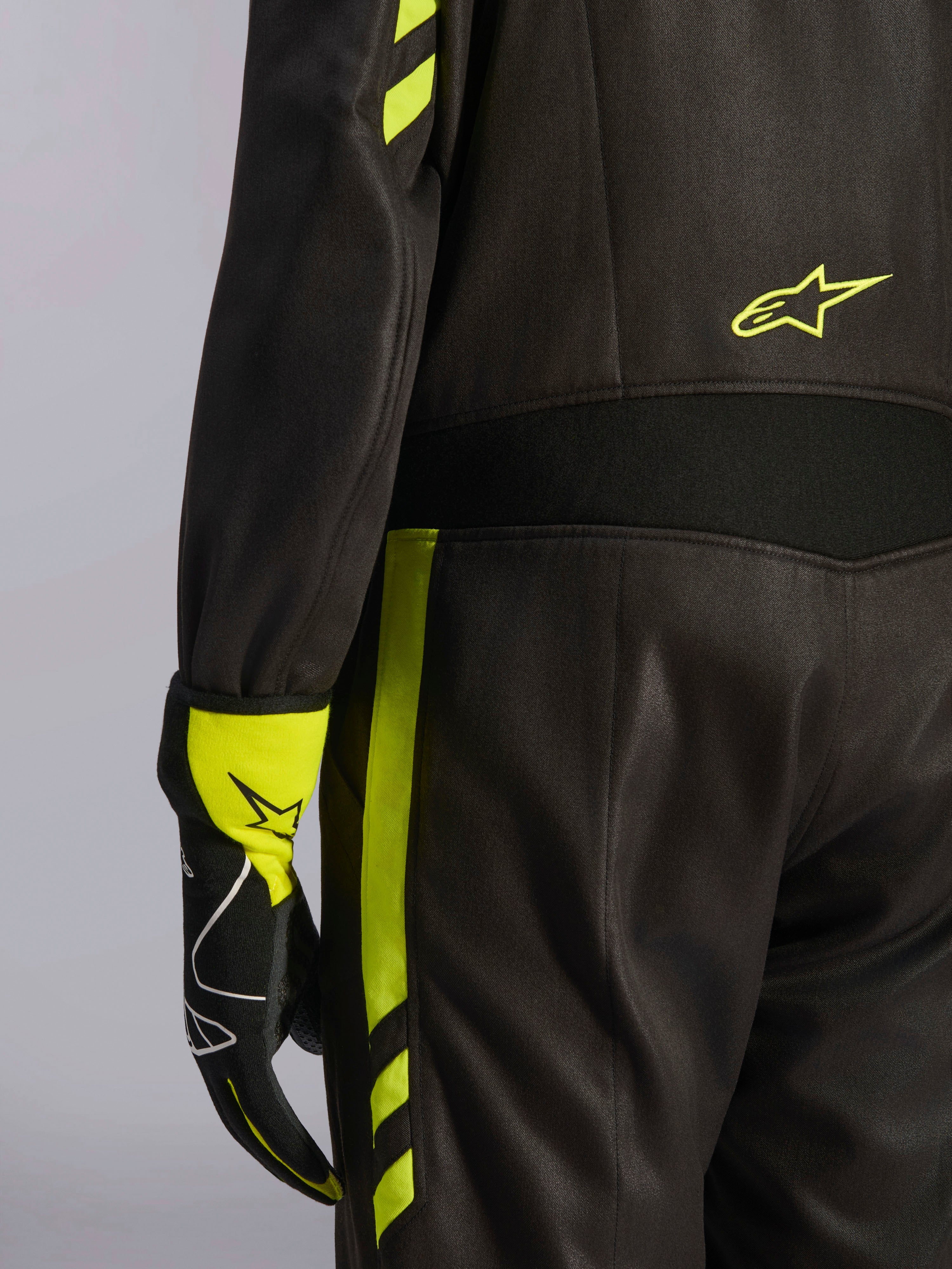 Alpinestars GP Race V3 Suit FIA, sort og gul fluo, nærbillede af detaljer på taljen og siden af benet, med aramid-strækpaneler og matchende racerhandske, professionelt bilsportsudstyr