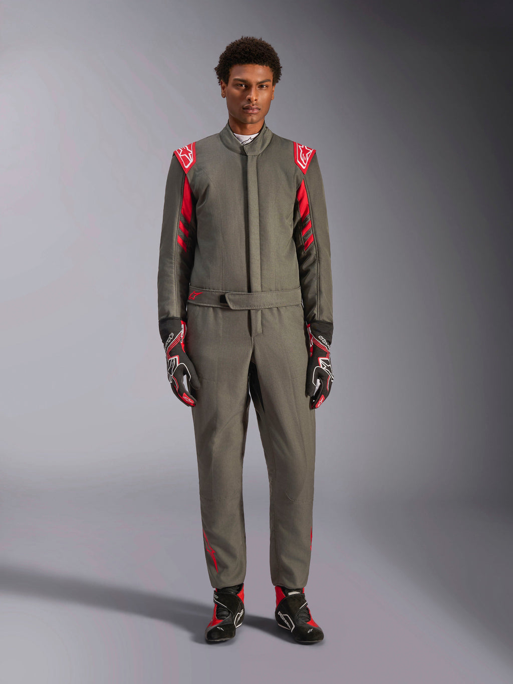 Alpinestars GP Race V3 Køredragt FIA, bilsportsdragt, antracit-rød, båret af en mandlig model med matchende handsker og støvler, med røde skulder-epauletter og branding, professionelt motorsportudstyr til præstationskørsel.