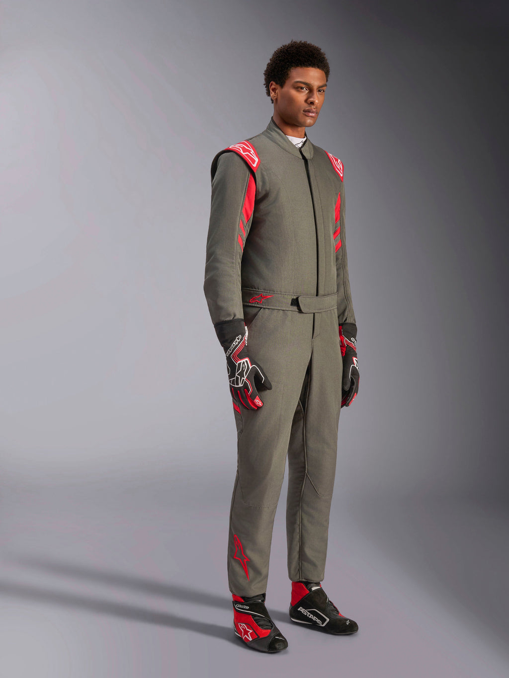 Alpinestars GP Race V3 Suit FIA, antracitgrå og rød køredragt til motorsport, båret med matchende racerhandsker og -sko, med røde skulder-epauletter og branding, strømlinet tolags teknisk design til motorsport