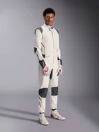 Male model wearing the Alpinestars Hypertech V3 Suit, White with Black and Silver accents, professional auto racing gear featuring black panels on shoulders and knees, styled with white and red racing gloves and white racing boots
