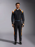 Alpinestars GP Pro Comp V2 FIA-dragt, Black Asphalt og Orange Fluo autoracerdragt, mandlig model iført fuldt beskyttelsesudstyr med matchende racerhandsker og -sko, hvide Alpinestars-logoer og markante orange sidepaneler, professionelt motorsportstøj