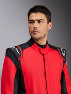 Mandlig model iført Alpinestars GP Pro Comp V2 FIA køredragt, rød og sort, med hvide Astars-logoer på skuldrene og detaljer med silikonegrebsteknologi, professionel beklædning til motorsport