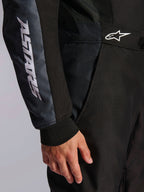 Alpinestars KMX-5 V3-dragt, kartingdragt, sort og Dark Shadow, nærbillede af detalje på hofte og arm, hvid ASTARS-branding på ærmet, hvidt logo i taljen, med mesh-paneler til ventilation og en strikket manchet ved håndleddet