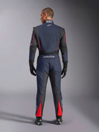Rear view of the Alpinestars GP Tech V4 Suit in Blue Navy Black Red, one-piece auto racing suit with black stretch panels and red accents, featuring Alpinestars branding and FIA certification details, worn with professional racing gloves and boots.