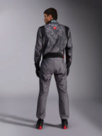 Alpinestars KMX-9 V3 Graphic 5 køredragt, kartingdragt, mørkegråt og sort kamuflagemønster på overkroppen, set bagfra med strækpaneler og Alpinestars-branding, båret med sorte handsker og sorte racersko med røde detaljer, professionelt motorsport-racerudstyr