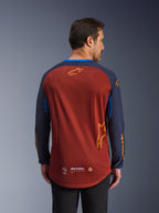 Alpinestars Maxdura Dual Jersey i Rust Brown og Mood Indigo, set bagfra, åndbar mesh-torso, mørkeblå ærmer med orange Alpinestars-branding og forlænget bagkant for ekstra dækning.