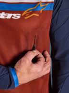 Nærbillede af Alpinestars Maxdura Dual Jersey, rustbrun mesh-torso med sømløs lynlåslomme på brystet, Mood Indigo-ærmer med integreret polstring, teknisk adventure-motorcykeltrøje-detalje