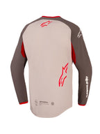 Alpinestars Maxdura Dual Jersey, set bagfra, farve Aluminum og Walnut med røde detaljer, har forlænget bagkant og fuld mesh-overkrop, røde Alpinestars-logoer på øverste og nederste del af ryggen, hvid branding på ærmet, adventure- og dual-sport motorcykelbeklædning