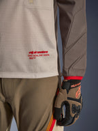 Alpinestars Maxdura Dual Jersey i Aluminum Walnut, detaljeret visning af den ventilerede mesh-overkrop med rød branding, slidstærkt ærme med integreret polstring, båret med koordinerede adventure-kørebukser og handsker
