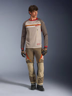 Alpinestars Maxdura Dual Jersey i Aluminum Walnut, adventure-motorcykeltrøje med sandfarvet mesh-krop og brune ærmer, rød krave og vandret bryststribe med Alpinestars-logo, båret med matchende adventure-bukser og handsker.