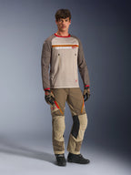 Model iført Alpinestars Maxdura Dual Jersey i Aluminum Walnut, med grå mesh-overkrop, brune ærmer med røde manchetter og brystlommer med lynlås, stylet med matchende off-road udstyr til adventure-kørsel.