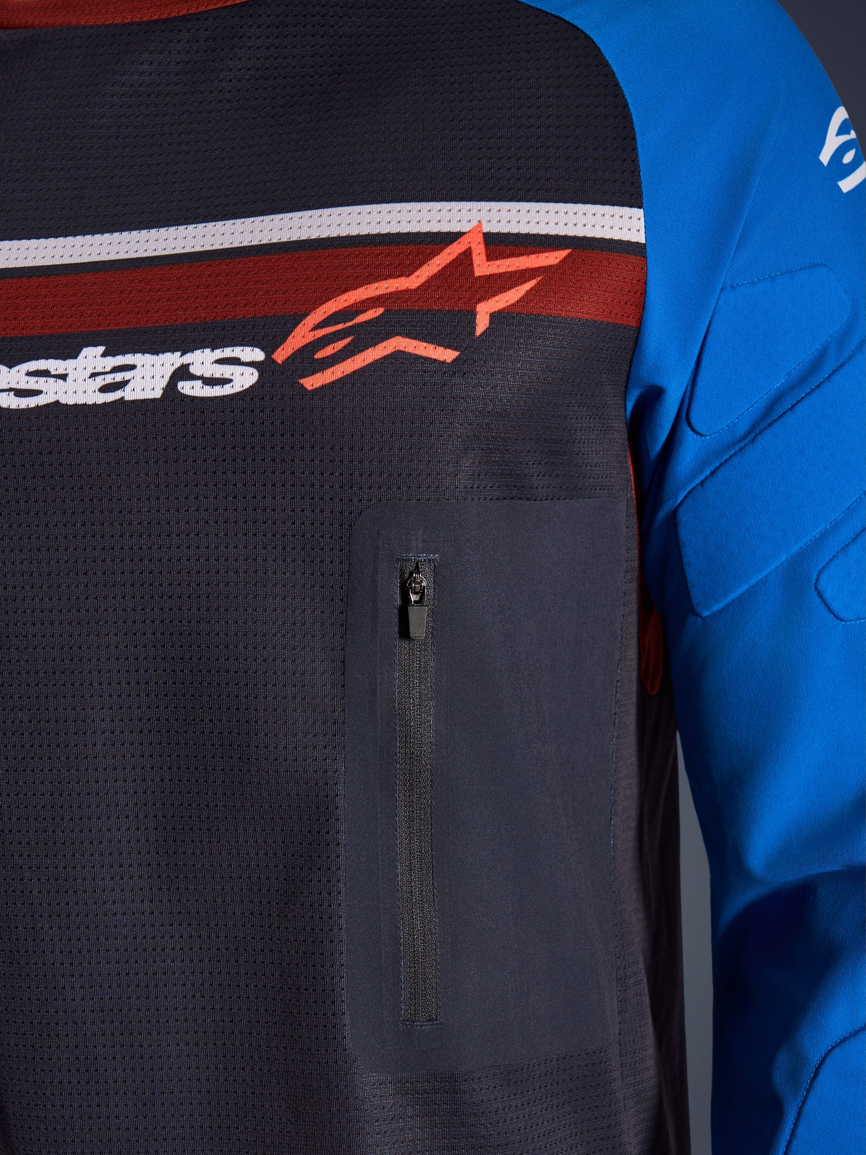 Alpinestars Maxdura Dual Jersey, nærbillede af bryst og ærme, mørkegrå og kongeblå, brystlomme med lynlås, åndbar mesh-overkrop og integreret polstring på ærmerne, Alpinestars-logo over røde og hvide striber.