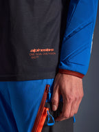 Nærbillede af Alpinestars Maxdura Dual Jersey i Deep Gray og Royal Blue, med orange logo og 'One Goal One Vision' tekst på mesh-overkroppen, polstret ærme med forstærkede geometriske paneler, teknisk adventure-køreudstyrsdetalje