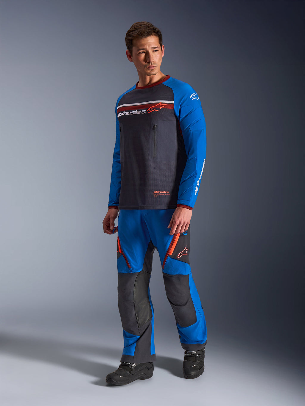 Alpinestars Maxdura Dual Jersey, Deep Gray og Royal Blue, adventure motorcykeltrøje med mesh-torso og royal blue ærmer, båret af en model med matchende off-road køre-bukser, brystlommer med lynlås og Alpinestars-branding.