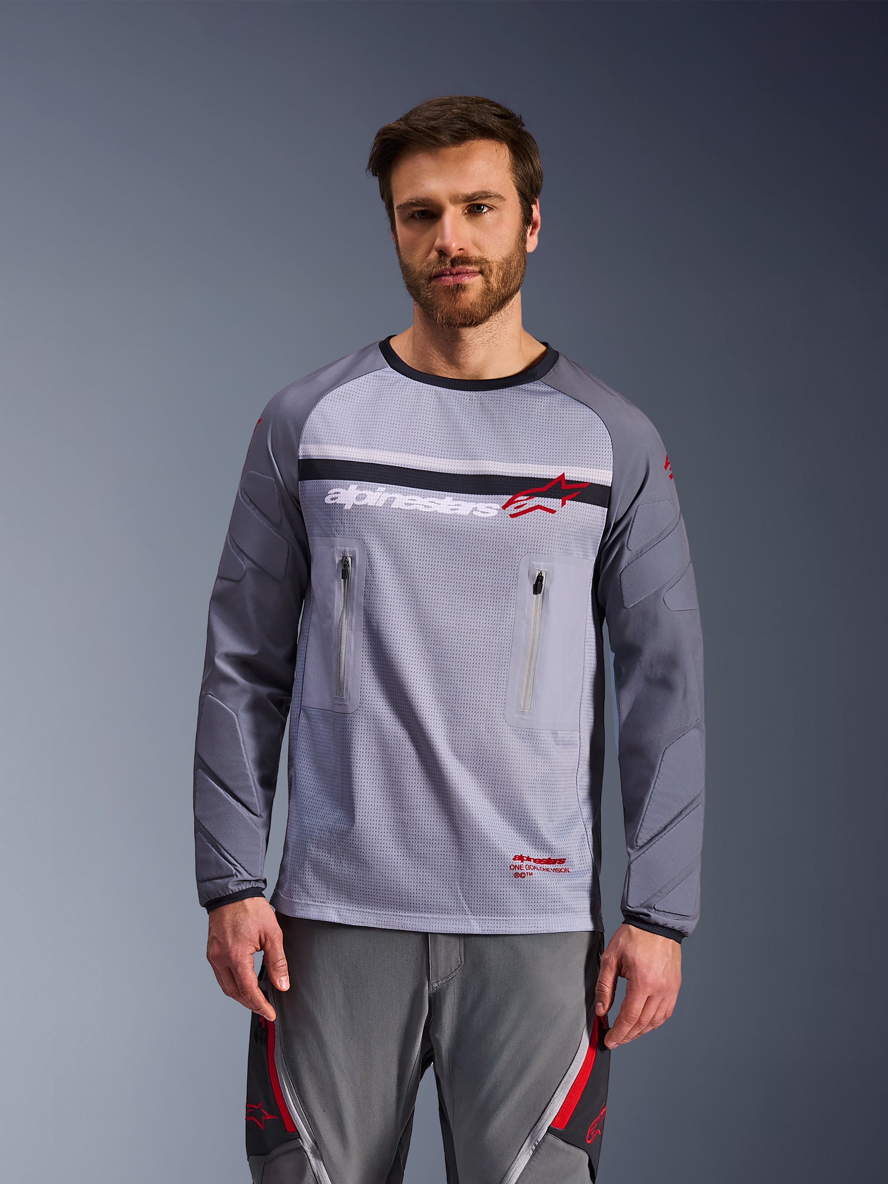 Alpinestars Maxdura Dual Jersey, adventure motorcykeltrøje, mellemgrå og mørkegrå, med mesh-overkrop, brystlommer med lynlås og slidstærke polstrede ærmer, hvidt og rødt logo på brystet, adventure off-road udstyr