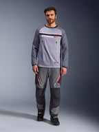Alpinestars Maxdura Dual Jersey, mellemgrå og mørkegrå, adventure-motorcykeltrøje med mesh-overkrop og brystlommer med lynlås, slidstærke ærmer med integreret polstring, båret med matchende grå performance-bukser med røde detaljer, teknisk off-road-køreudstyr