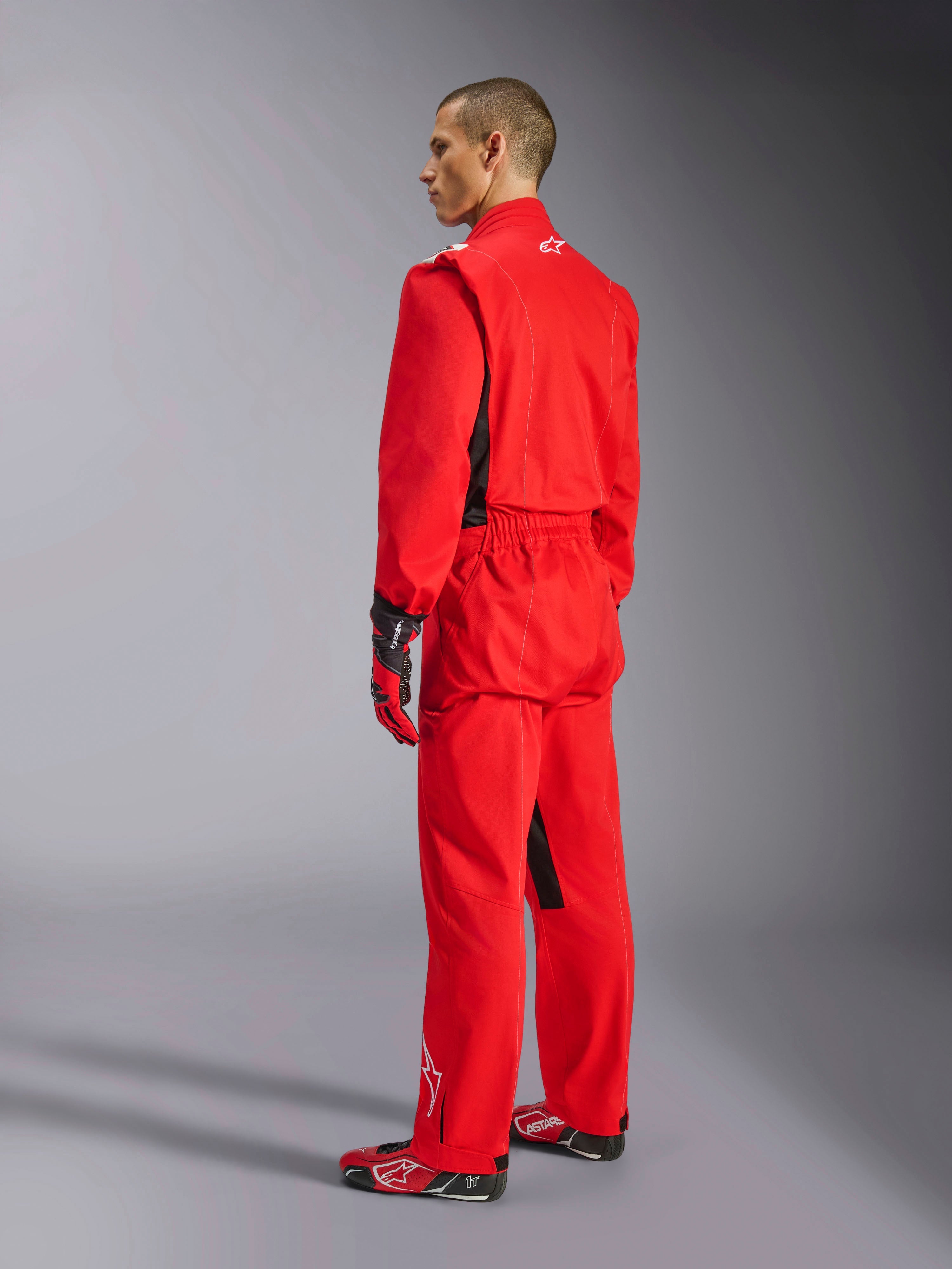Alpinestars Kart Indoor V2 Suit, rød karting-køredragt, set bagfra fra siden på en model, båret med matchende røde handsker og racersko, enkeltlags poly-bomuldstwill-konstruktion, professionelt motorsportudstyr til indendørs karting
