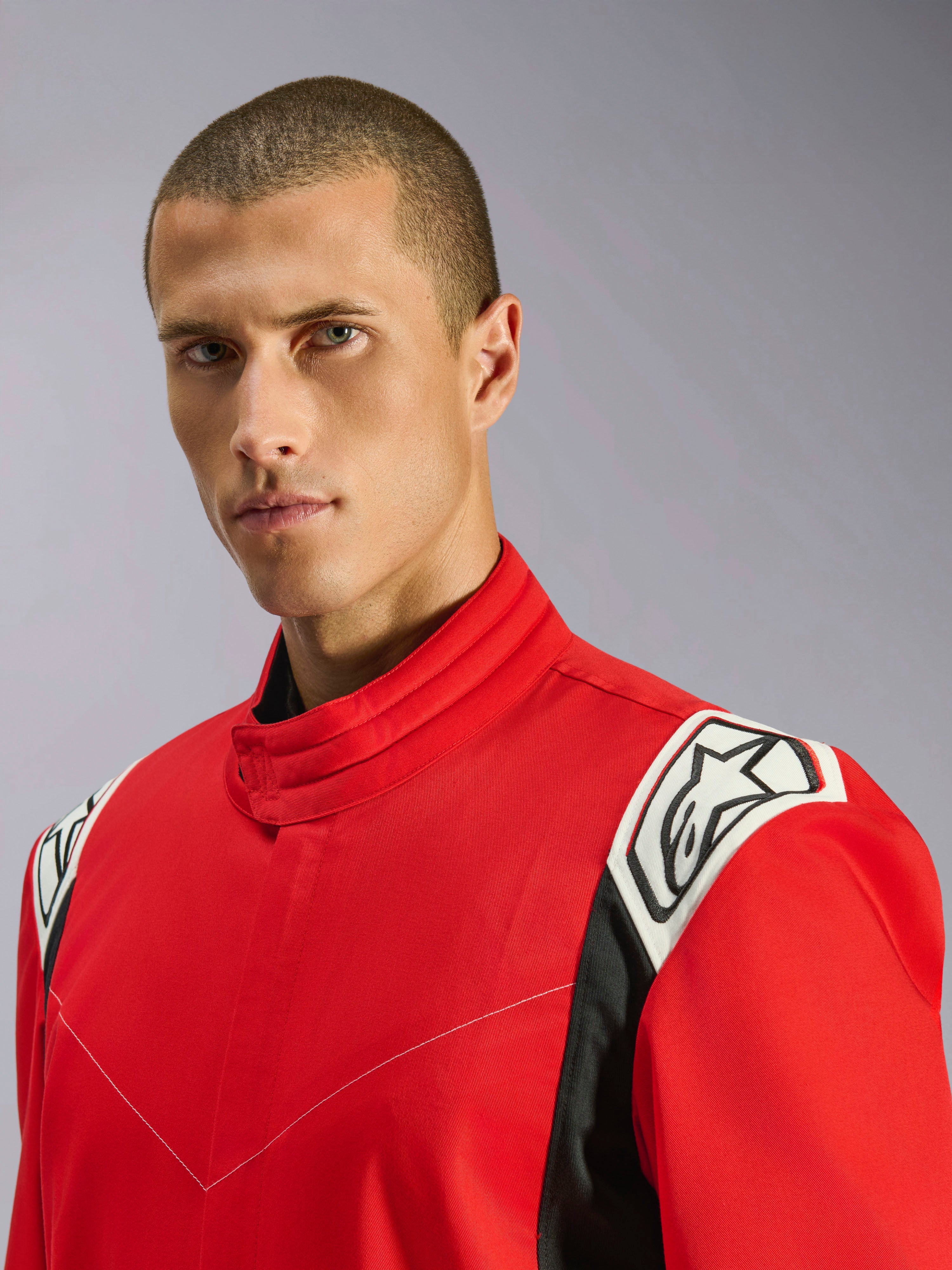 Alpinestars Kart Indoor V2 Suit i rød, nærbillede af mandlig model iført dragten, der fremhæver den ergonomiske krave og hvide og sorte skulderdetaljer med Alpinestars-logoet.