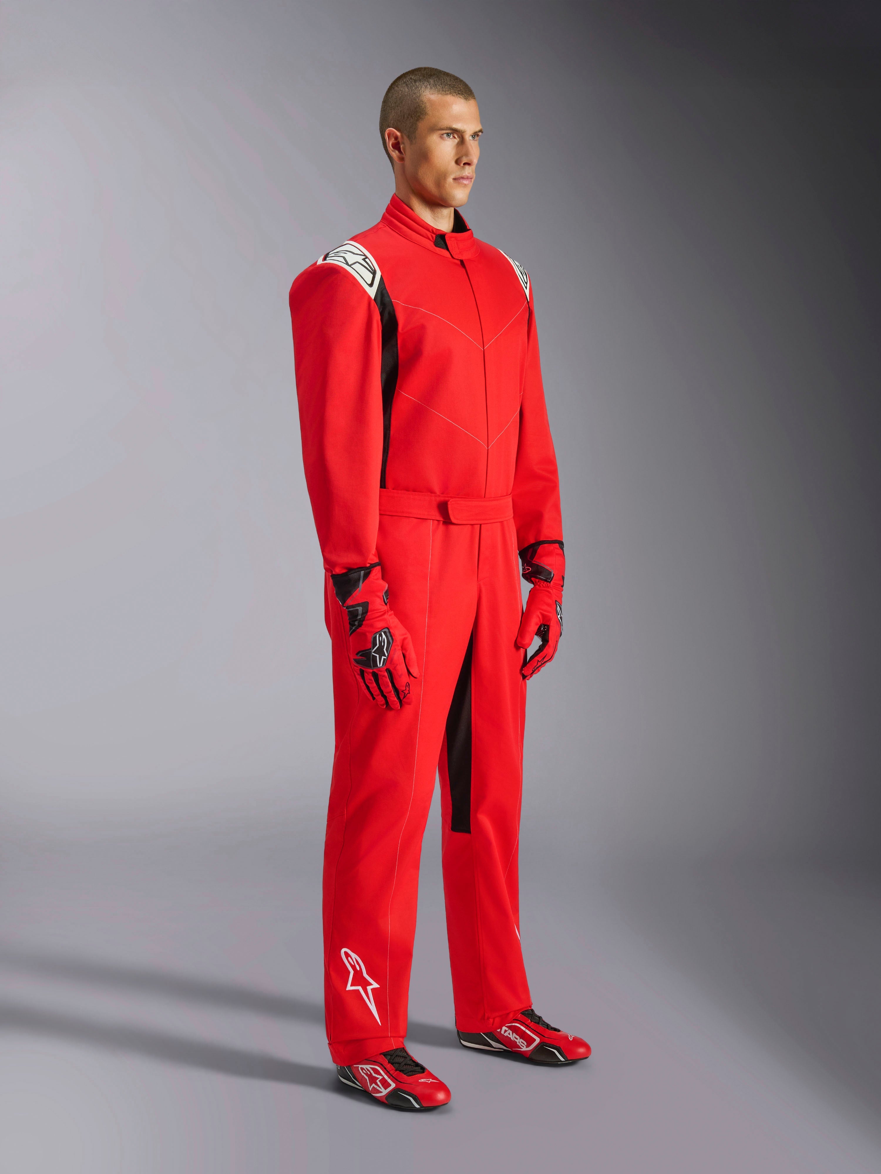 Alpinestars Kart Indoor V2 Suit, rød kartingdragt, båret af en model med matchende røde og sorte handsker og sko, med hvide logoer på skuldre og underben, sorte detaljer, designet til rekreativ karting og indendørsbaner