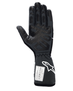Alpinestars Tech-1 Race V4 Gloves, Professional Auto Racing Gloves, Black Tar Gray, palm side view featuring extensive silicone grip patterns on fingers and palm, extended gauntlet cuff with white Alpinestars logo and FIA/SFI certification labels