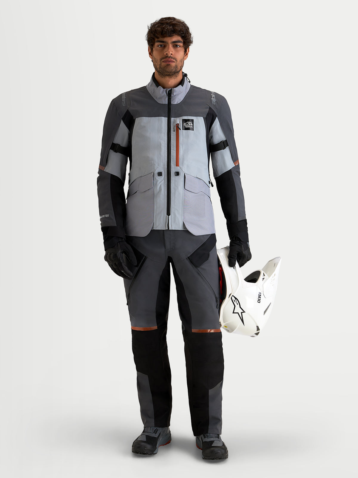 Alpinestars St-7 V2 2L Gore-Tex jakke, herre adventure-motorcykeljakke i mellemgrå og sort, vandtæt tekstilkonstruktion med CE-certificeret beskyttelse, båret af model der holder hvid hjelm