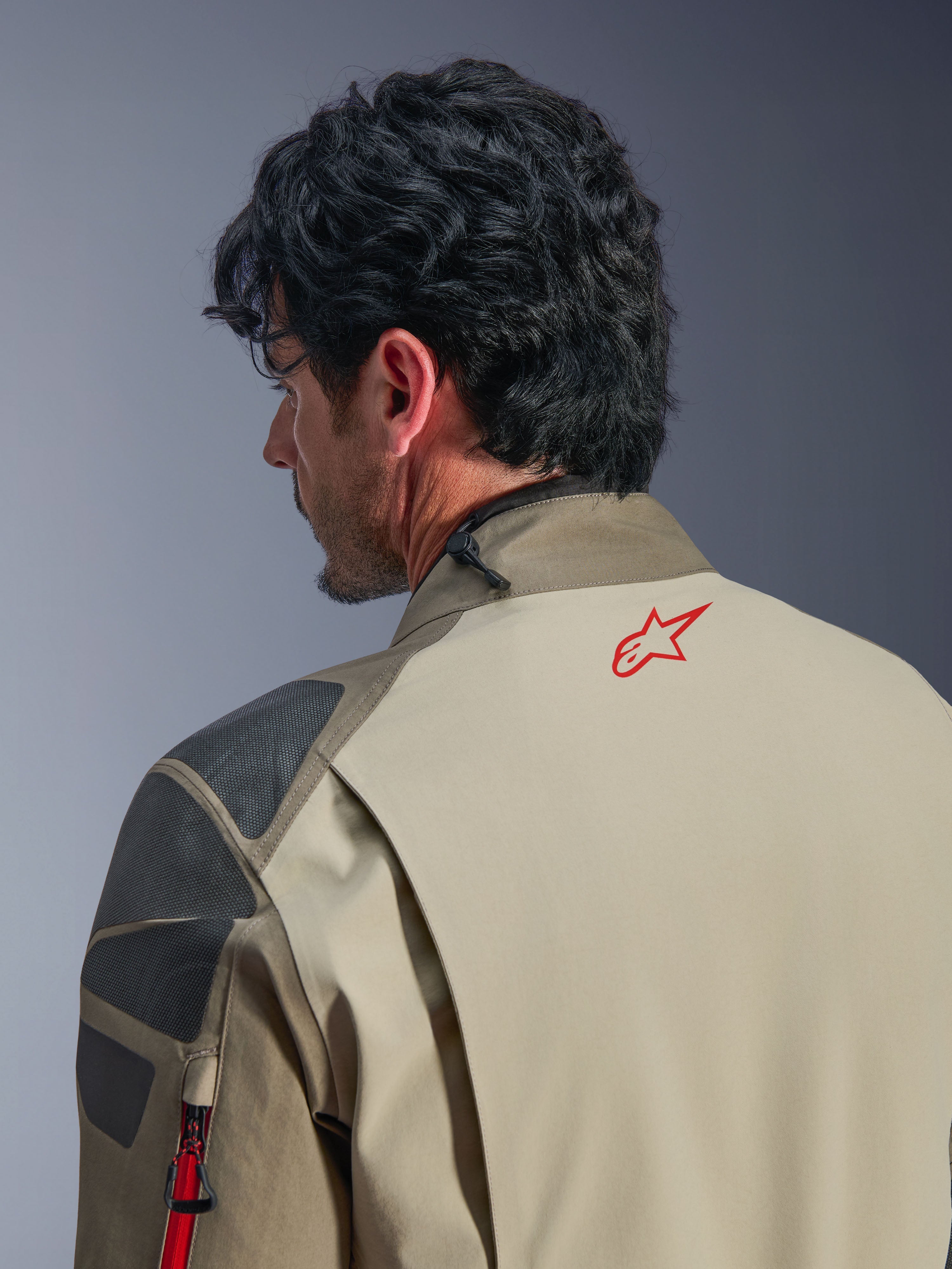 Alpinestars Nazca 3L GORE-TEX PRO jakke, Walnut Rock Brown adventurejakke, nærbillede af ryggen og skulderen, rødt stjernelogo i nakken, grå teksturerede forstærkningspaneler, slidstærk tekstilkonstruktion til motorcykelkørsel