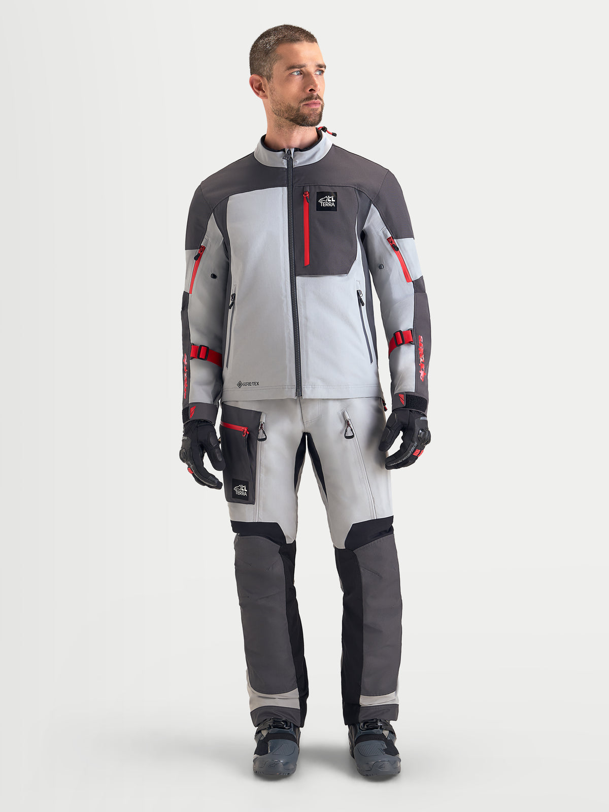 Alpinestars Arenis Gore-Tex® gear set, herre adventure-motorcykeljakke og -bukser i lysegrå, mørkegrå og rød, set forfra på model iført vandtæt køretøjseret udstyr