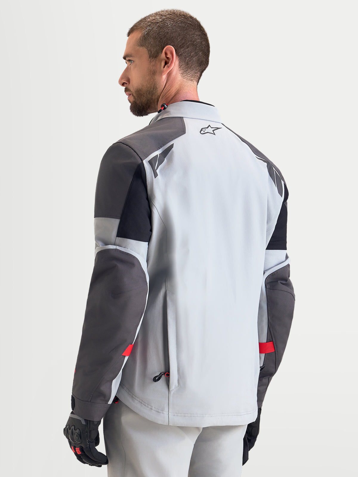 Alpinestars Arenis Gore-Tex jakke, herre adventure-motorcykeljakke i mellemgrå, mørkegrå og sort, set bagfra der viser vandtæt tekstilkonstruktion og reflekterende skulderdetaljer, båret af mandlig model
