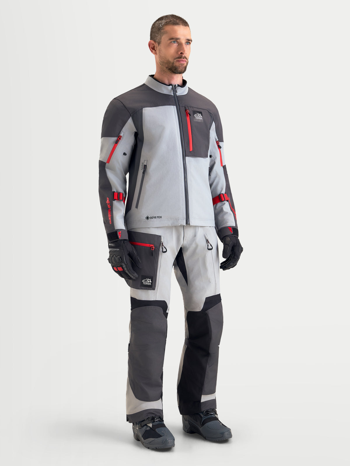 Alpinestars Arenis Gore-Tex udstyrssæt, herre adventure-motorcykeljakke og -bukser i lysegrå og mørkegrå med røde detaljer, frontvisning af mandlig model iført matchende vandtæt touring-udstyr