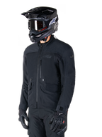Alpinestars St-7 Prime GORE-TEX-jakke, sort motorcykeljakke, båret af en rytter med sort hjelm og beskyttelsesbriller, med store cargolommer på brystet og en lamineret vandtæt skal, premium udstyr til adventure touring og pendling