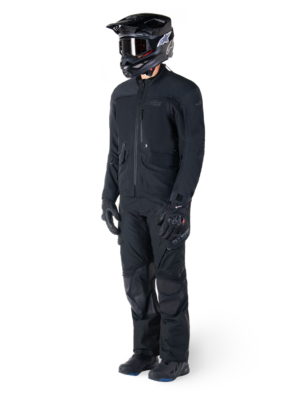 Motorcyklist iført Alpinestars St-7 Prime GORE-TEX-jakke i sort, koordineret adventure touring-outfit med matchende sorte bukser, sort hjelm med goggles og handsker, med et strømlinet og funktionelt design til ydeevne i al slags vejr.