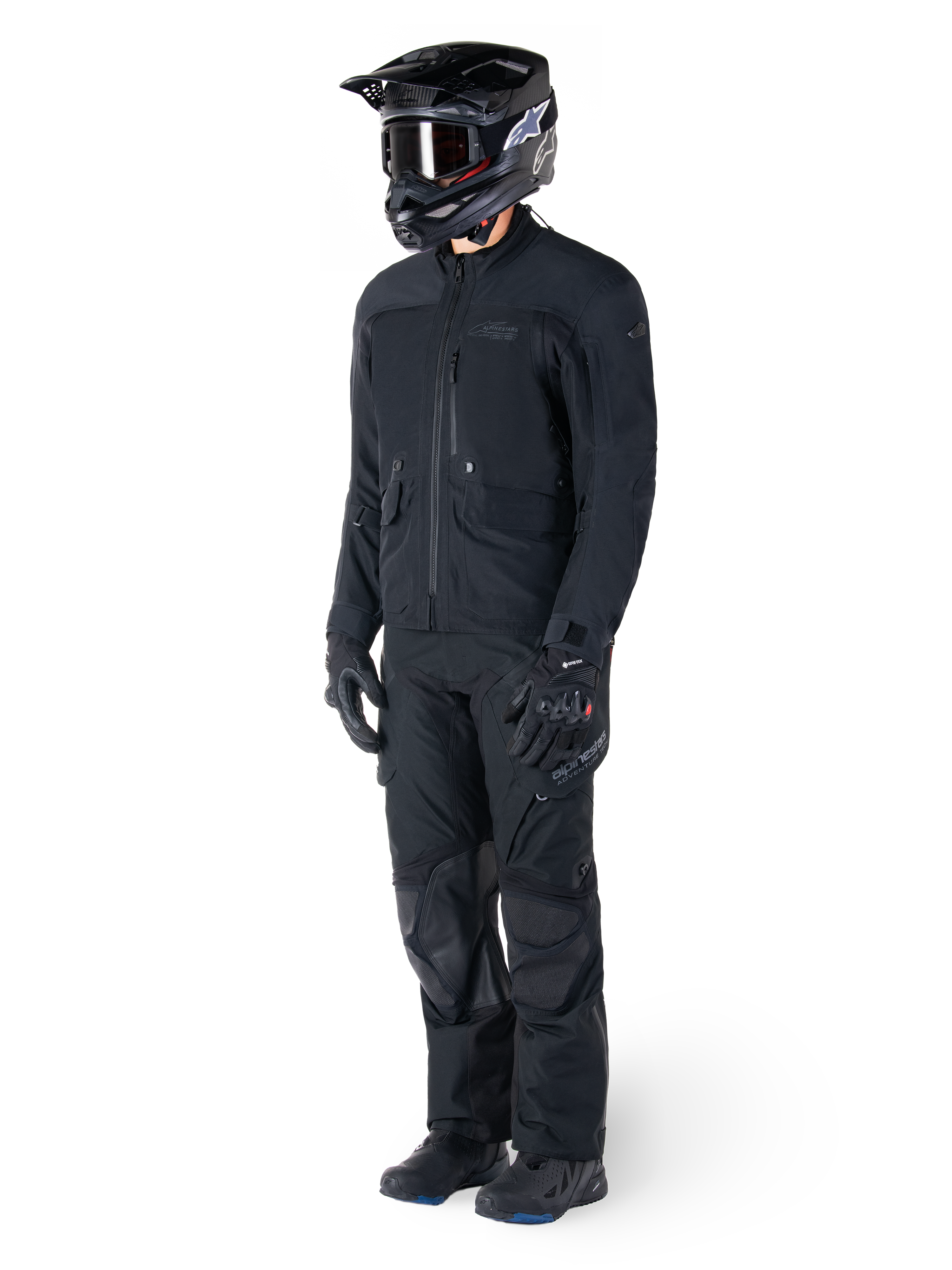 Motorcyklist iført Alpinestars St-7 Prime GORE-TEX-jakke i sort, koordineret adventure touring-outfit med matchende sorte bukser, sort hjelm med goggles og handsker, med et strømlinet og funktionelt design til ydeevne i al slags vejr.